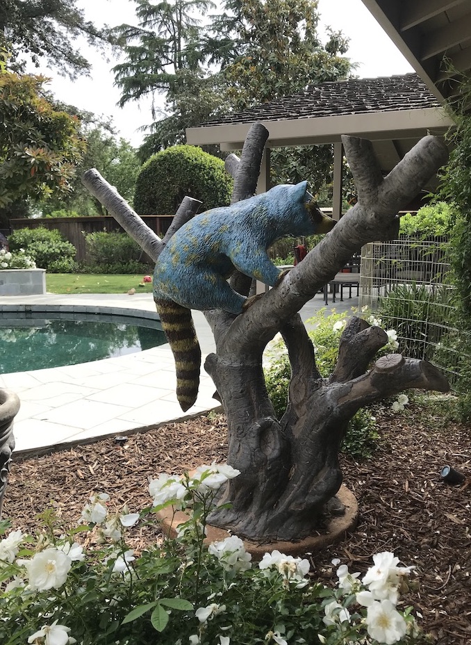 Whimsical Garden Sculpture of Turquoise Raccoon in Tree